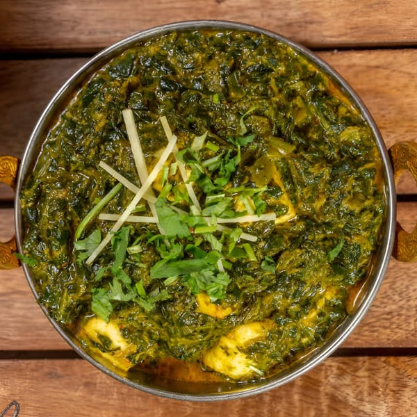 Palak Paneer, a vibrant green Indian spinach and cheese curry, garnished with ginger and cilantro.