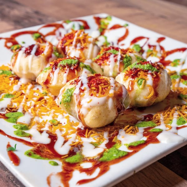 A plate of Bombay Street Foods' dahi puri, topped with yogurt, chutneys, and crunchy sev.