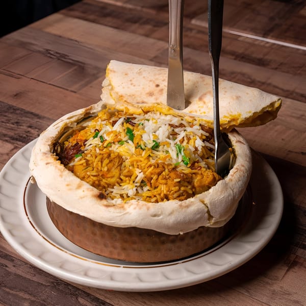 Bombay Street Foods' chicken biryani, a flavorful rice dish, served in a traditional pot with naan bread.