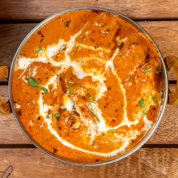 Top-down view of Bombay Street Foods' butter chicken, a rich orange curry with white cream swirls.