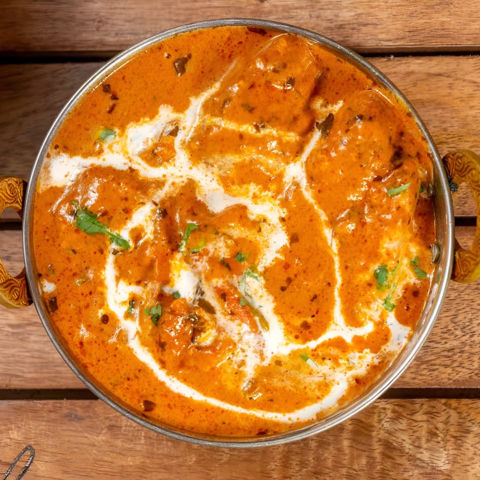 Top-down view of Bombay Street Foods' butter chicken, a rich orange curry with white cream swirls.