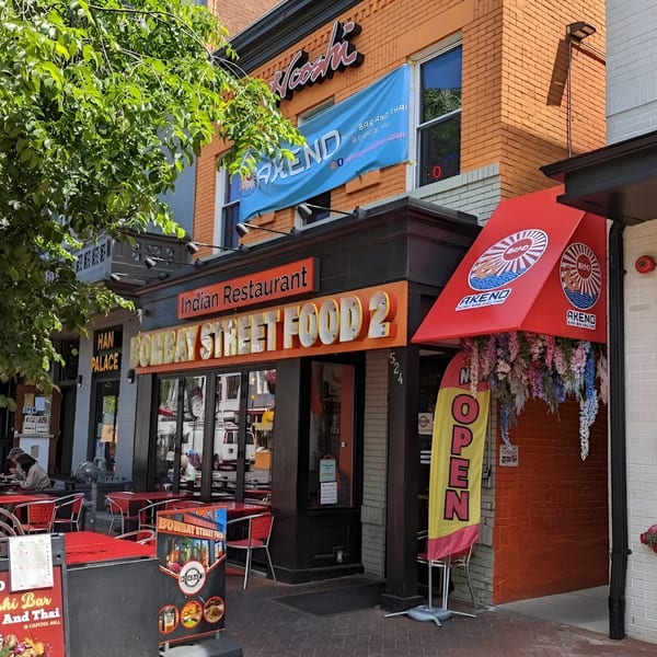 Exterior of Bombay Street Food 2, an Indian restaurant with outdoor seating and a red awning.